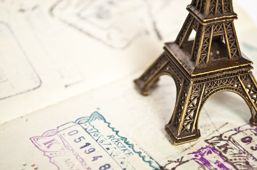 Фигурка Эйфелевой башни на фоне паспорта со штампами